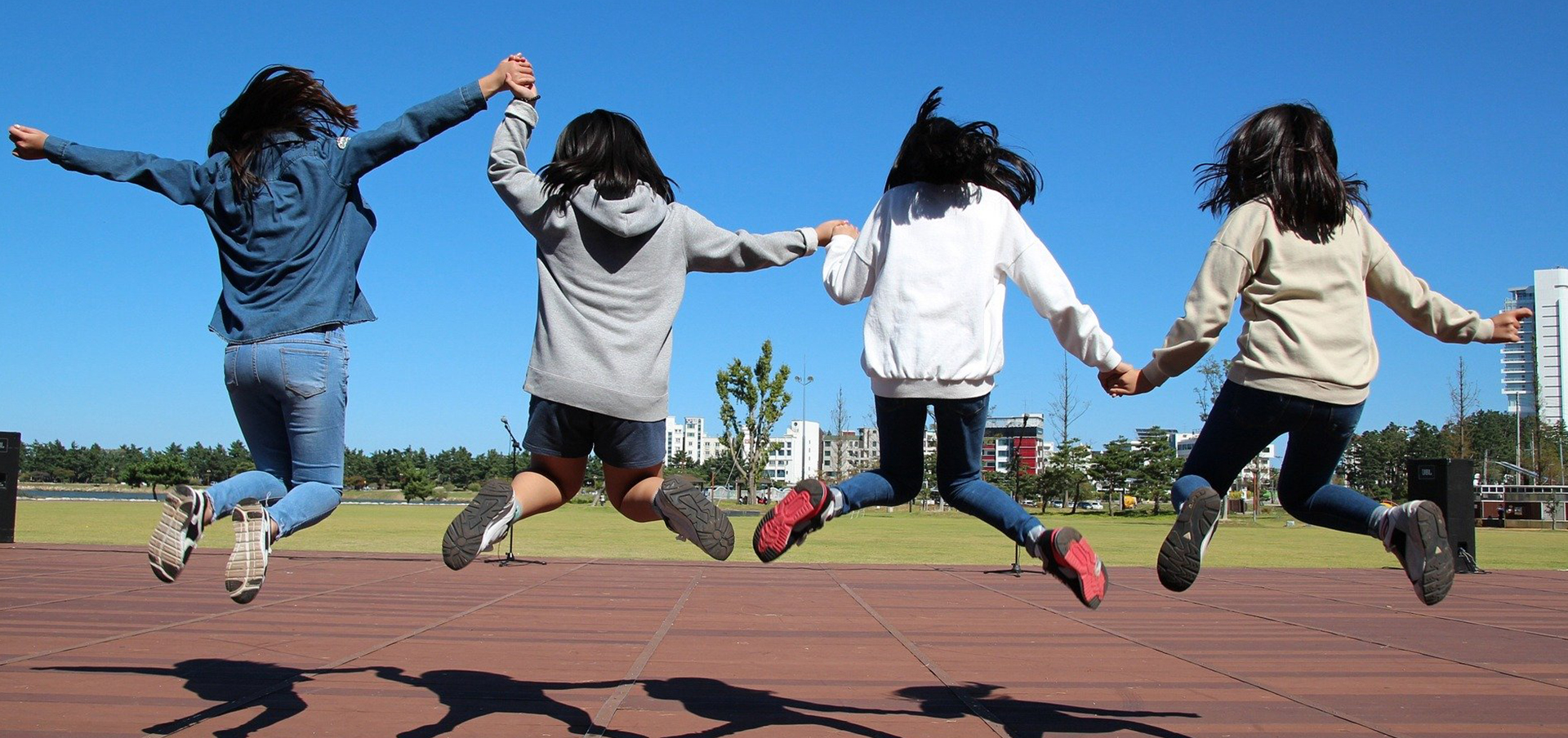Preteen girls jumping while holding hands
