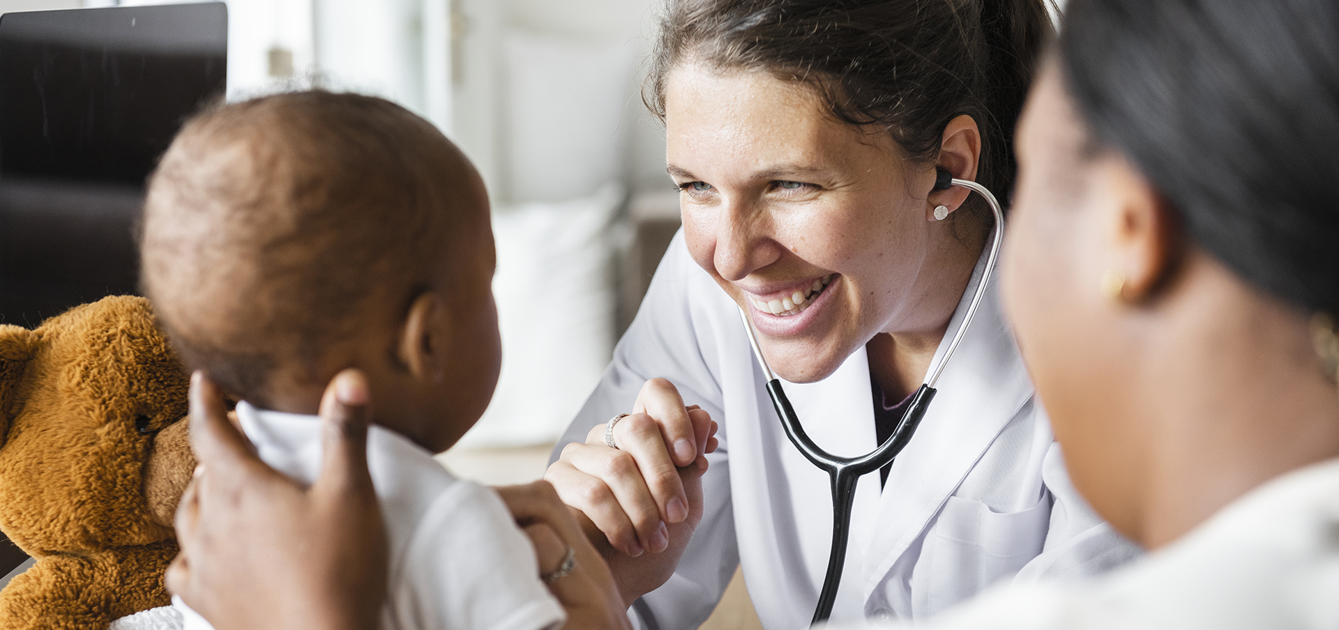 White Doctor smiling at black infant 