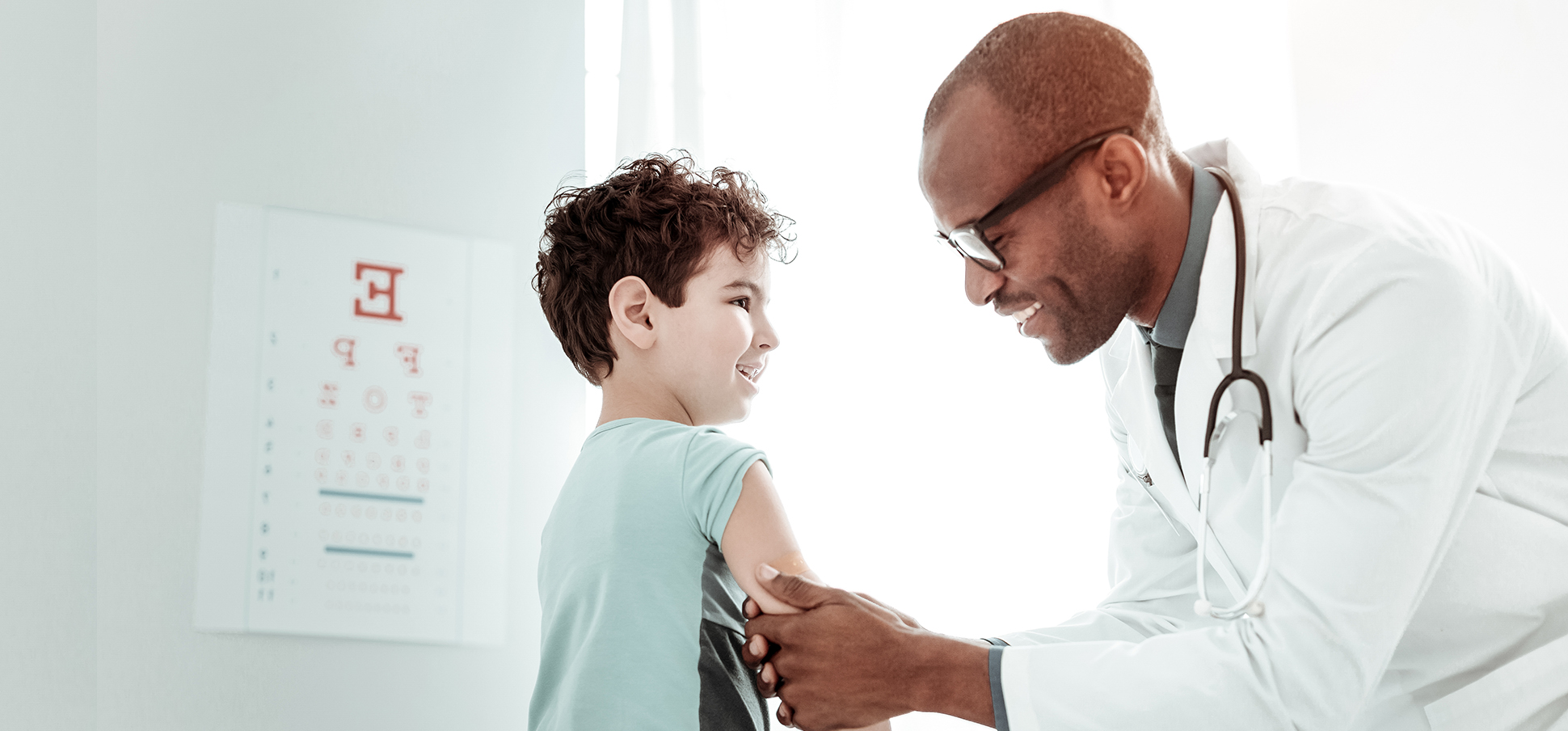 Black doctor examining white young boy